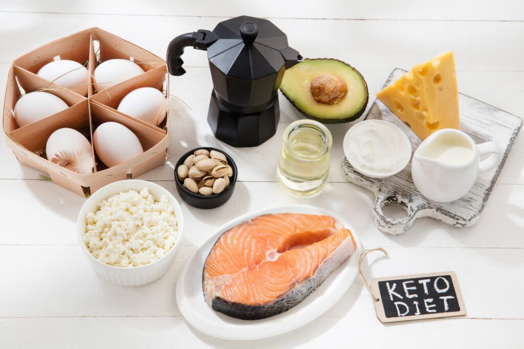 저탄고지 식단. KETO DIET 문구가 적혀 있으며, 달걀, 연어, 흰 쌀, 견과류, 아보카도, 크림, 치즈 등이 나열되어 있다.