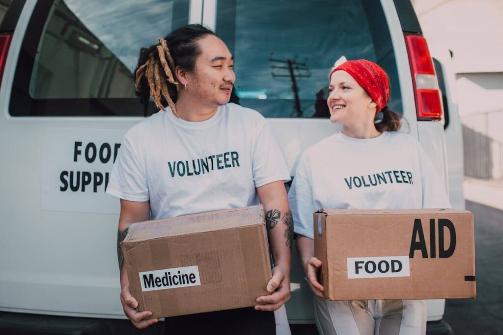 자원봉사자가 약품과 음식 상자를 들고 웃고 있는 이미지. 자원봉사를 통한 나눔과 기부 행동은 옥시토신을 증가시킨다.