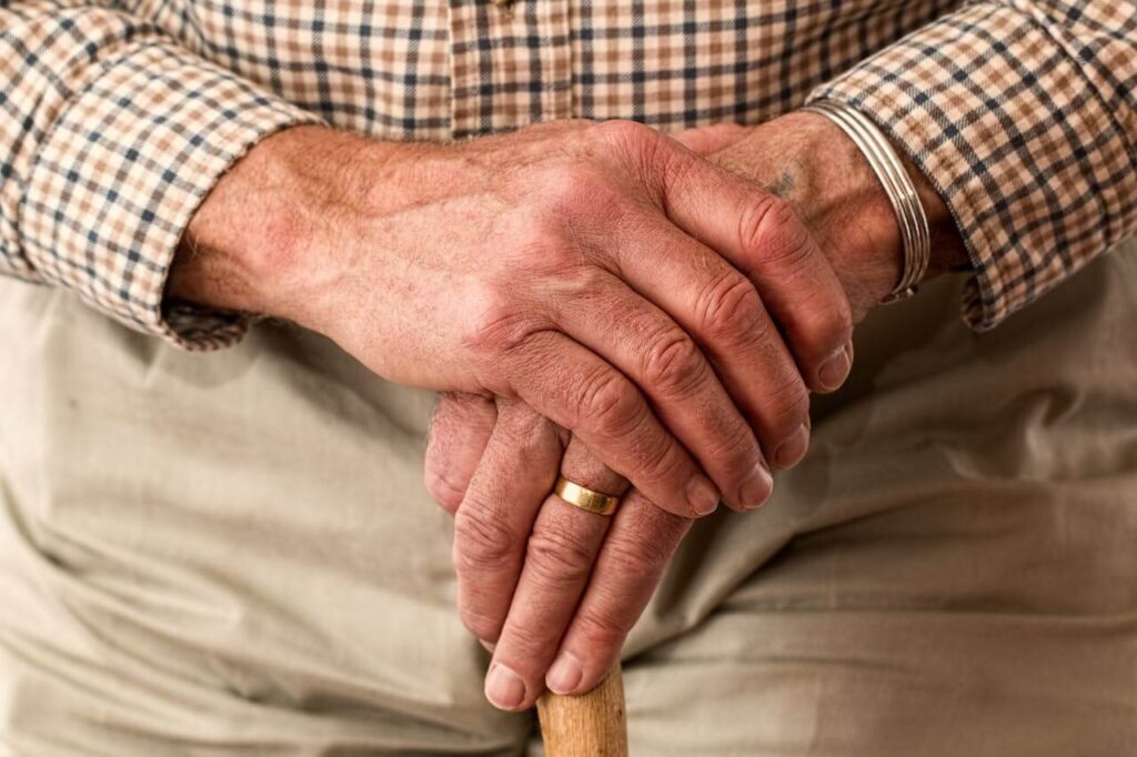 노인이 지팡이를 양손으로 잡고 있는 이미지.